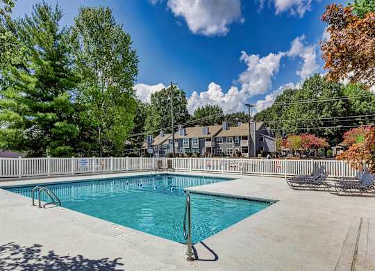 A large swimming pool surrounded by trees and a fence. at Brandemere Apartment Homes, Winston Salem, NC, 27106