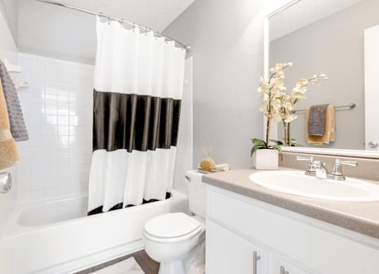 a bathroom with a white toilet next to a bathtub with a black and white shower curtain at Bridges at Mallard Creek Apartment Homes, Charlotte, NC, 28269