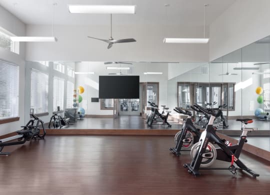 a workout room with exercise bikes and a tv