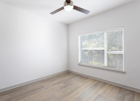 a bedroom with a large window and wood flooring