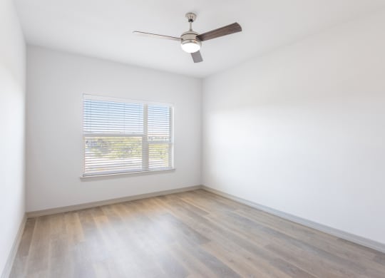 an empty room with white walls and wood floors and a ceiling fan
