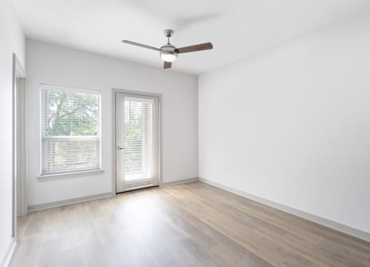 an empty living room with white walls and a ceiling fan