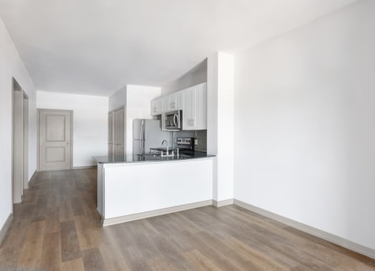 a living room and kitchen with white walls and wood floors