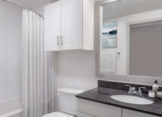 a bathroom with white cabinets and black countertop