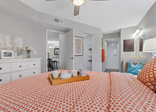 A bedroom with a bed, dresser, and ceiling fan.