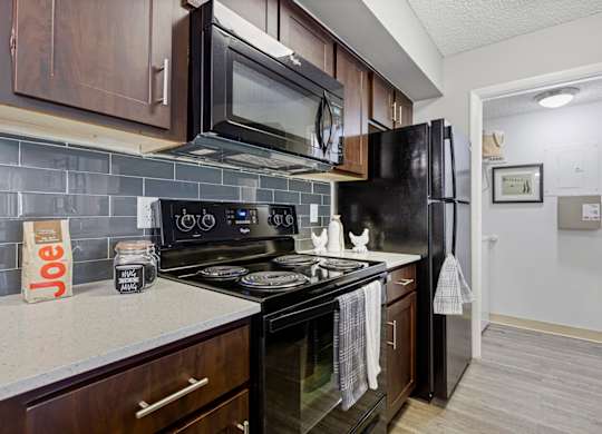 A kitchen with black appliances and brown cabinets