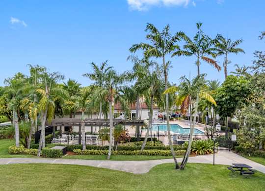 A swimming pool surrounded by palm trees and the resident clubhouse