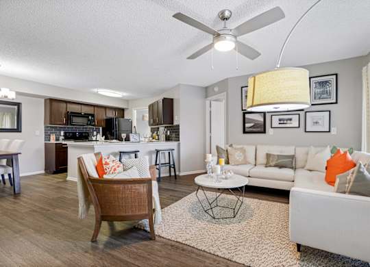 A living room hardwood-style flooring and a ceiling fan