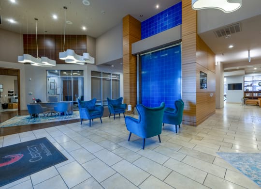a lobby with blue chairs and a blue waterfall in the center
