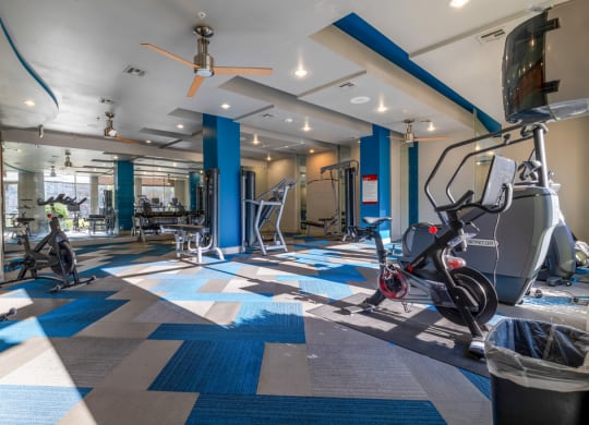 a gym with treadmills and other exercise equipment in a building with blue pillars