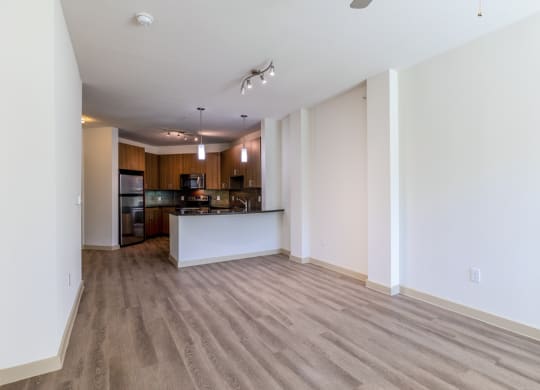 an empty living room and kitchen with wood flooring