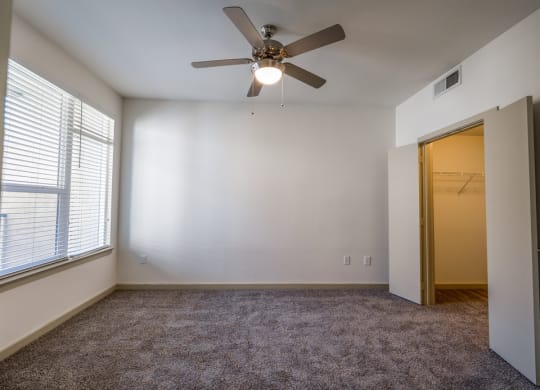 an empty room with a ceiling fan and a door to a closet