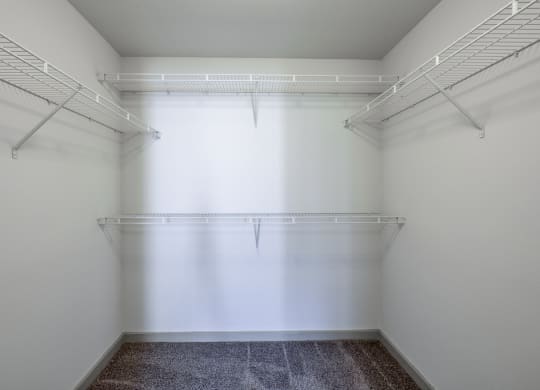a walk in closet in a white room with a window