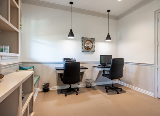 Resident business center with computers and a bookshelf and sitting area