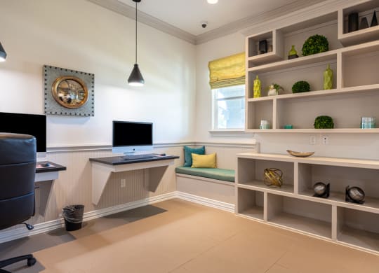 Resident business center with computers and a bookshelf and sitting area