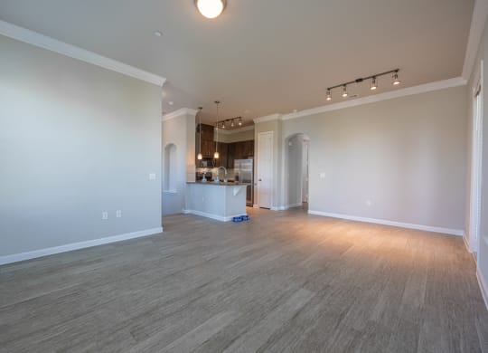 Living room with hardwood flooring facing kitchen with stainless steel appliances