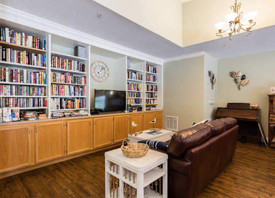 A living room with a brown couch, a white coffee table, and a bookshelf filled with books.