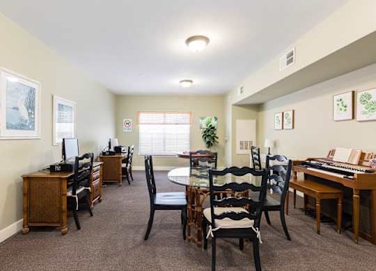 A room with a desk, chairs, and a computer.