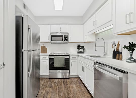 a kitchen with white cabinetry and stainless steel appliances at Caveness Farms Apartments, Wake Forest 