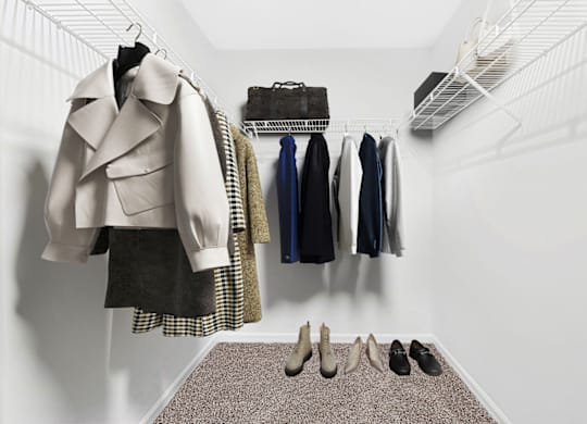 a walk in closet with white walls and a gray rug at Caveness Farms Apartments, Wake Forest, NC 27587