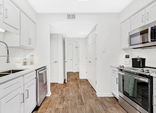 a kitchen with white cabinetry and a wooden floor at Caveness Farms Apartments, Wake Forest North Carolina 