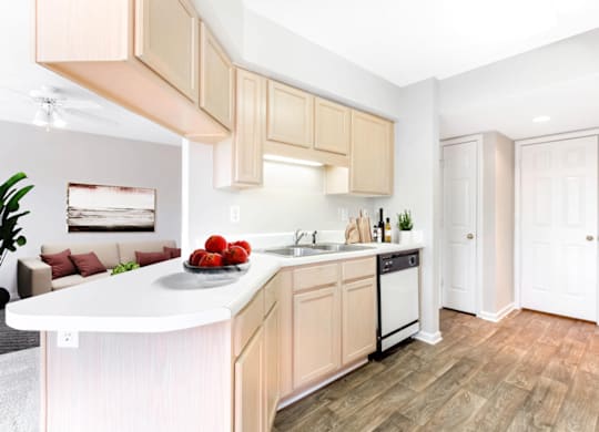 a kitchen with wooden cabinets and a bowl of fruit on the counter at Caveness Farms Apartments, North Carolina 