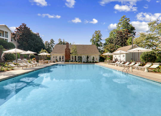 a swimming pool with lounge chairs and umbrellas at Caveness Farms Apartments, Wake Forest North Carolina 