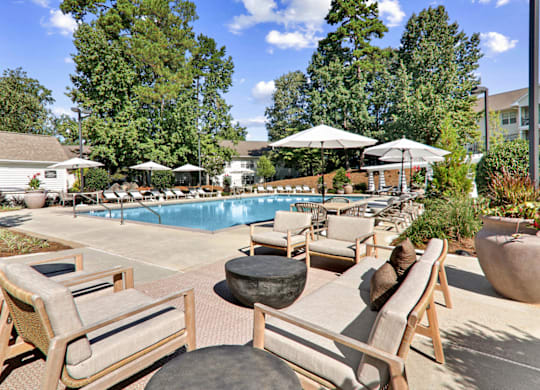 a swimming pool with lounge chairs and umbrellas at Caveness Farms Apartments, Wake Forest, NC 