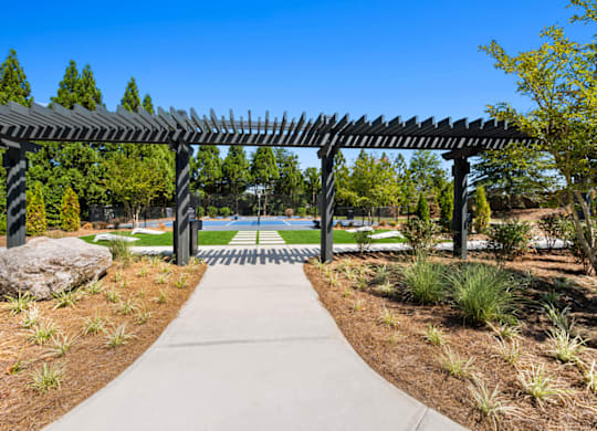 a pergola in a park with a tennis court in the background at Caveness Farms Apartments, North Carolina, 27587