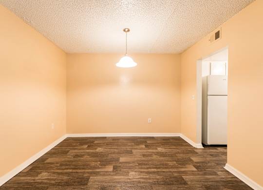 A room with a wooden floor and a white refrigerator.