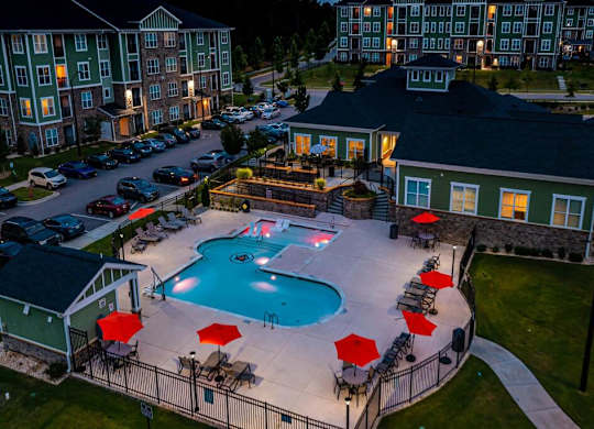 A pool surrounded by a black fence and red umbrellas at Foxwood Apartments, Raleigh-Durham, NC