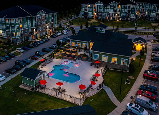 A large building with a pool in front of it at Foxwood Apartments, Raleigh-Durham, 27616