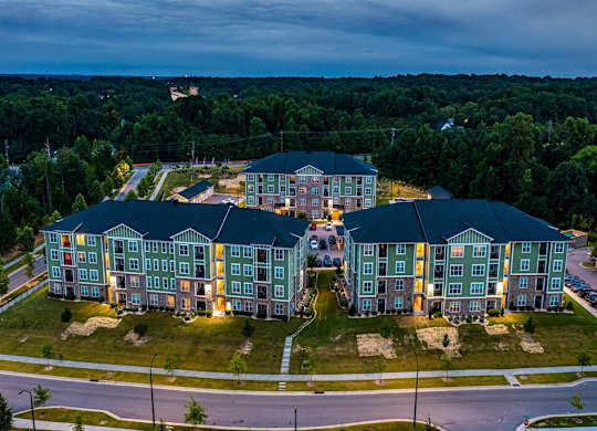 A large apartment complex with multiple buildings and lit windows at Foxwood Apartments, Raleigh-Durham