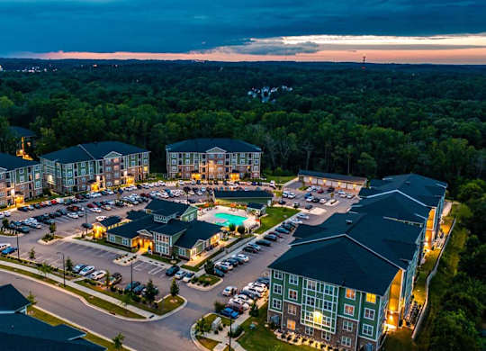 A large, well-lit residential complex at dusk with a parking lot in the foreground. at Foxwood Apartments, North Carolina, 27616