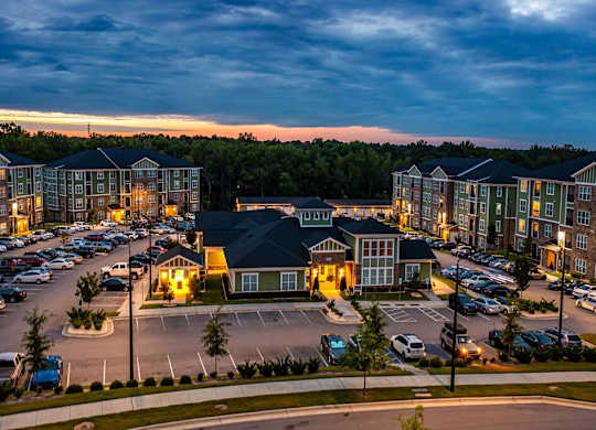 A parking lot with cars and a building with a lit up number 6 at Foxwood Apartments, North Carolina, 27616