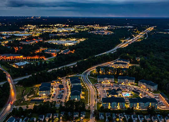 A nighttime aerial view of a residential area with a lit-up road and houses at Foxwood Apartments, Raleigh-Durham, North Carolina