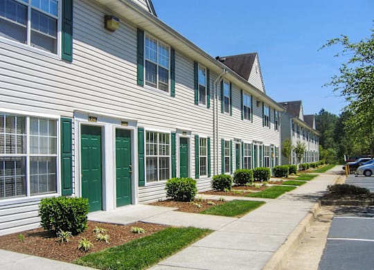 a long white building with green doors and shutters