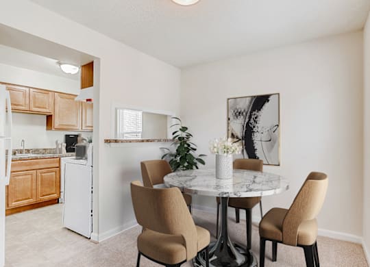a dining area with a table and chairs and a kitchen in the background
