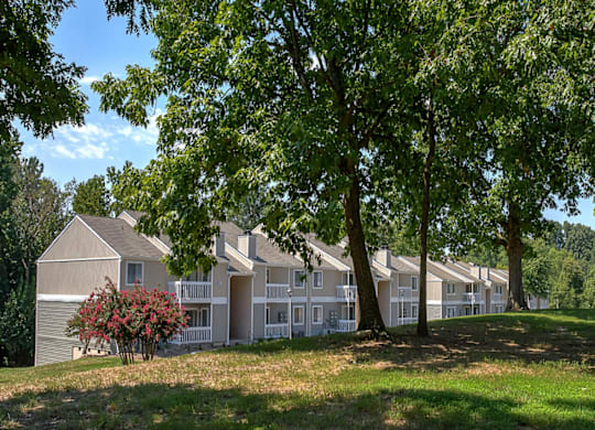 a large grassy area with trees in front of an apartment complex at Eastchester Ridge Apartments, High Point