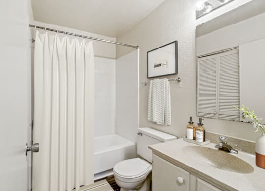 a bathroom with a white shower curtain and a white toilet next to a white sink at Eastchester Ridge Apartments, North Carolina, 27262