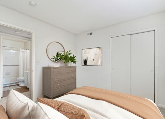 a bedroom with white walls and a bed with an orange blanket at Eastchester Ridge Apartments, North Carolina, 27262