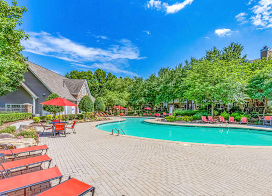 a swimming pool with chaise lounge chairs and trees in the background