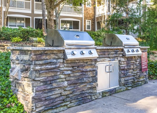 a backyard barbecue area with a stone wall and two stoves