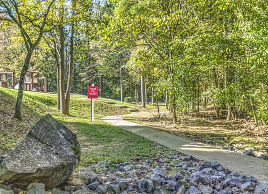 a path through a park with a red sign in the background