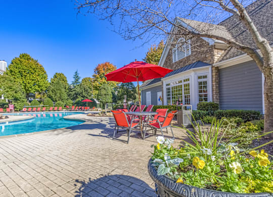a patio next to a pool with a table and chairs and a umbrella