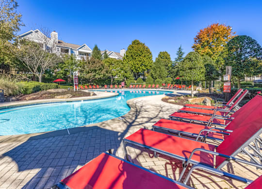 a pool with lounge chairs and trees in the background