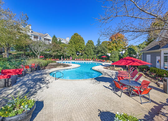 a pool with lounge chairs and umbrellas at the enclave at woodbridge apartments in sugar