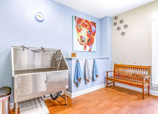 a stainless steel sink and bench in a laundry room with a painting of a dog on the