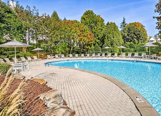 a resort style swimming pool with lounge chairs and umbrellas