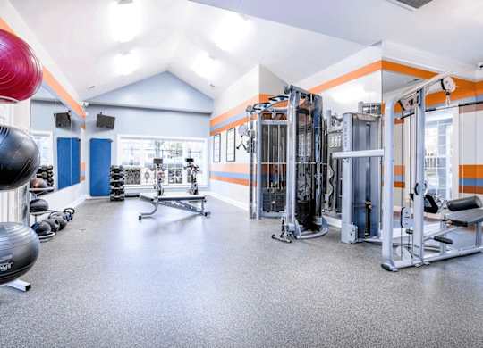 A gym with a variety of equipment including a squat rack, a leg press machine, and a rowing machine.